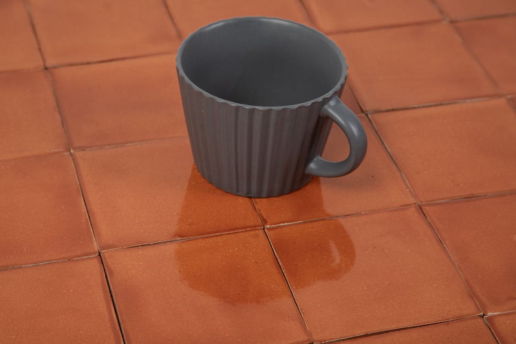Graue Tasse auf quadratischen Bodenfliesen