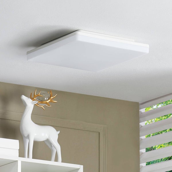 Quadratische LED Deckenleuchte an weißer Decke in hellem Raum mit beige Wand und dekorativer Hirschfigur auf weißem Regal.