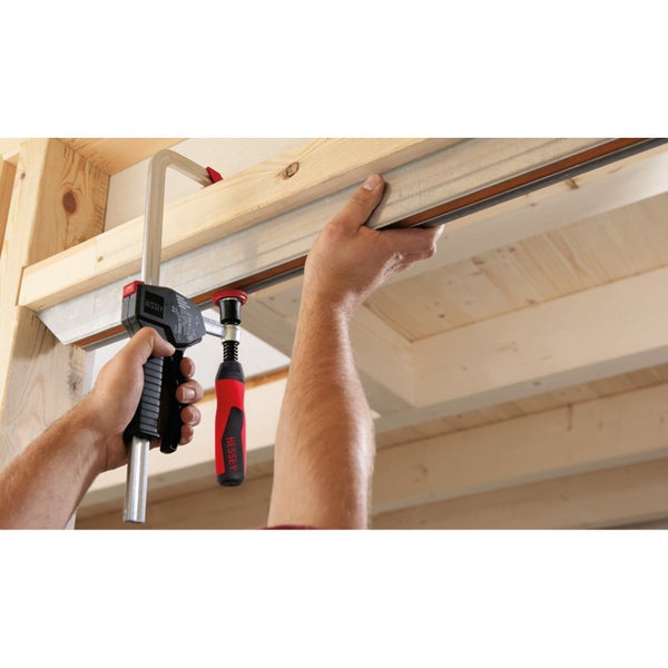 Person befestigt Holzkonstruktion mit einer Schraubzwinge