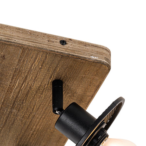 Detailansicht einer Deckenleuchte mit Holzplatte und schwarzem Lampenkörper.