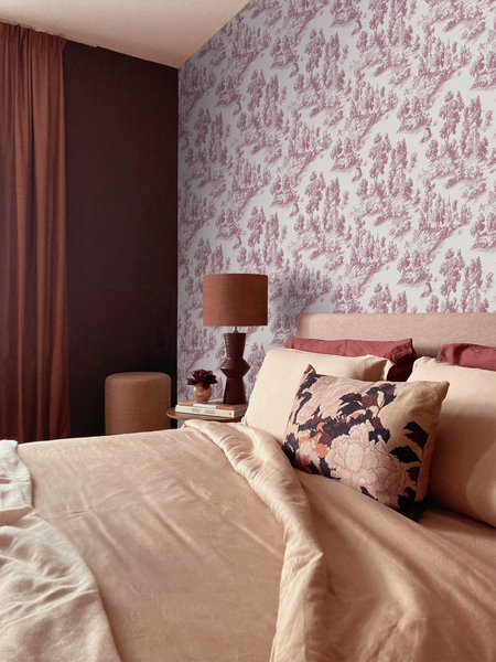 Schlafzimmer mit Toile-de-Jouy-Tapete mit Waldmotiv. Bett mit beiger Bettwäsche, Blumenkissen, Nachttisch mit Lampe und dunkle Vorhänge.