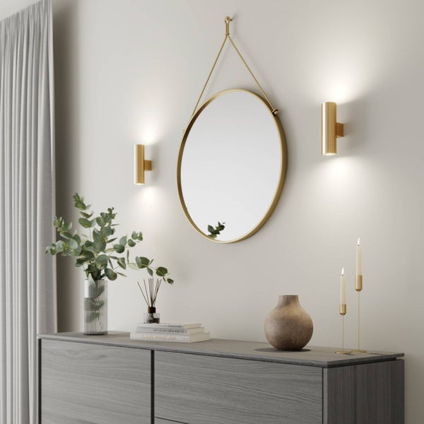 Wohnraum mit ovalem Spiegel, Wandleuchten und Kommode