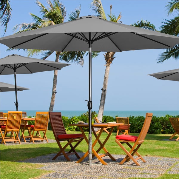 Szene mit Gartentischen, Stühlen und Sonnenschirmen in einem Außenbereich.