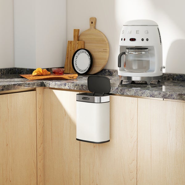 Küchenszene mit Mülleimer, Kaffeemaschine und Frühstücksutensilien auf einer Arbeitsplatte.