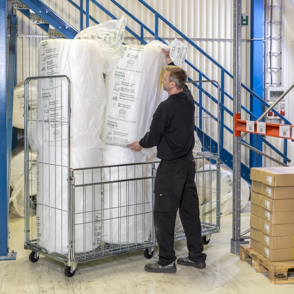 Mann mit Rollwagen voller Luftpolsterfolie in einem Lager