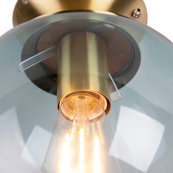Nahaufnahme einer Deckenleuchte mit Glasschirm und Messingdetails