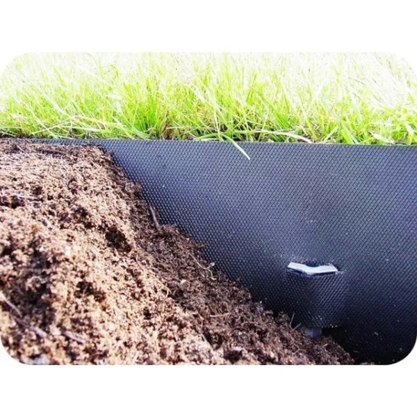 Nahaufnahme eines Hochbeets mit Erde, Gras und einer schwarzen Beetumrandung