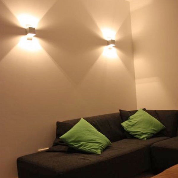 Wohnzimmer mit grauer Couch, grünen Kissen und zwei Wandleuchten