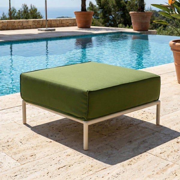 Quadratischer Gartenhocker mit grünem Sitzpolster und hellem Metallgestell auf einer hellen Steinterrasse am Pool.