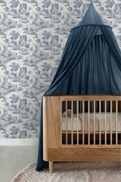 Vliestapete mit Toile-de-Jouy-Muster in einem Kinderzimmer mit Holzbabybett und Baldachin.
