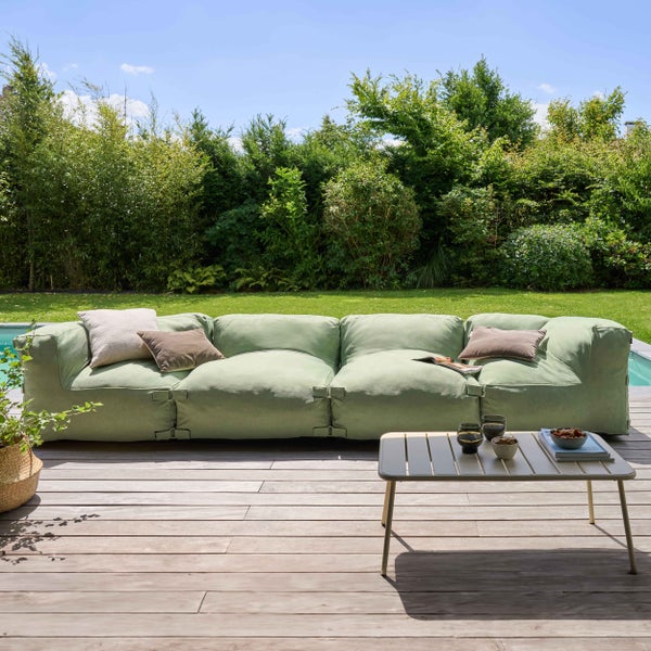 Modernes grünes Outdoor-Loungesofa auf einer Holzterrasse im Garten neben einem Pool mit einem kleinen Metallbeistelltisch.