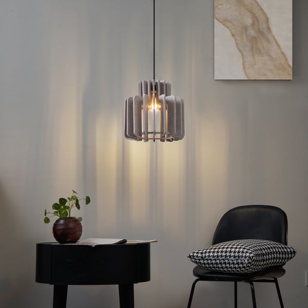 Moderne Pendelleuchte mit Schirm aus grauen Filzlamellen in einem Wohnzimmer neben einem schwarzen Stuhl und Beistelltisch.