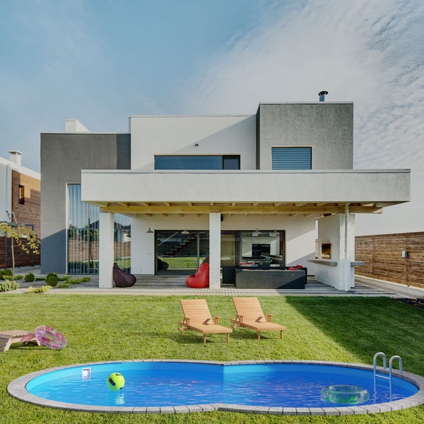 Moderner Garten mit Pool, Liegestühlen und Outdoor-Lounge vor einem Wohnhaus