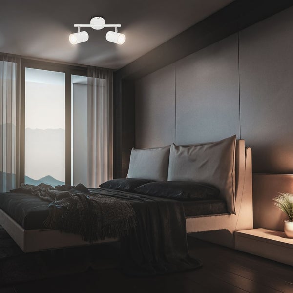 Modernes Schlafzimmer mit einer zweiflammigen, verstellbaren Deckenleuchte, einem Bett mit dunkler Bettwäsche und großem Fenster mit Bergblick.