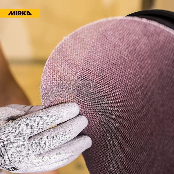 Mirka Logo und eine Hand mit Schutzhandschuh beim Halten einer runden Netzschleifscheibe.