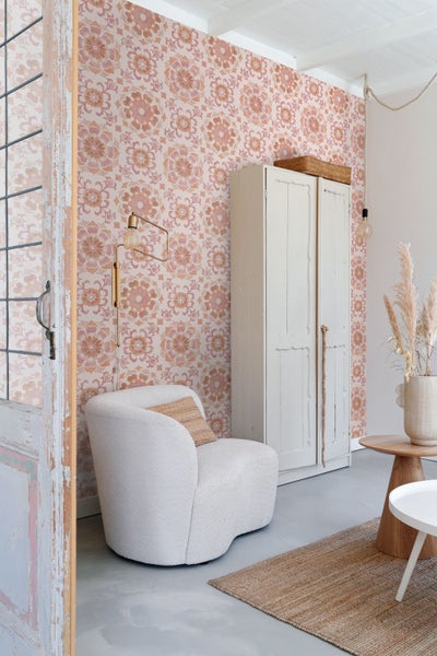 Gemütlicher Raum mit blumiger Tapete, Sessel, Schrank und Holztisch