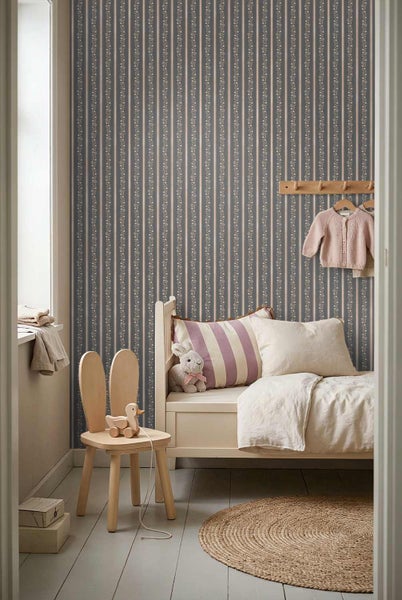 Vliestapete mit floralem Streifenmuster in einem hellen Kinderzimmer mit Holzbett und Hasenstuhl.