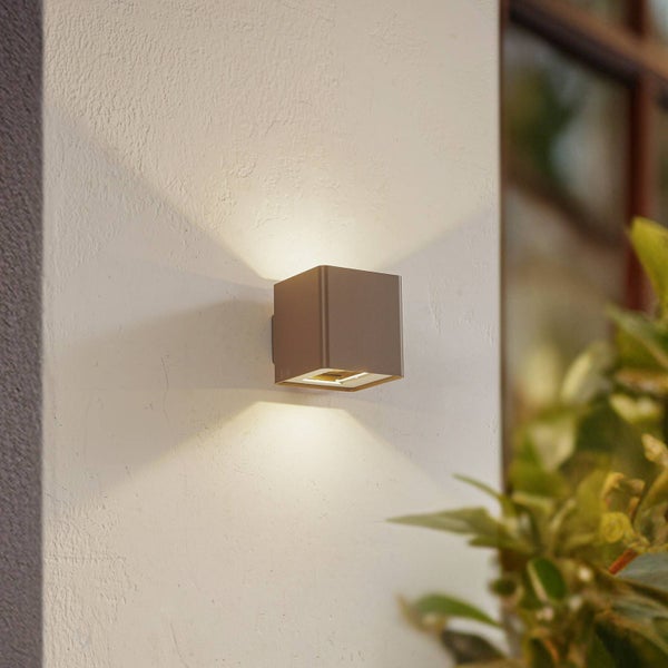 Würfelförmige Außenwandleuchte mit Lichtstrahl nach oben und unten an einer hellen Hauswand.