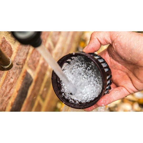 Eine Hand hält einen runden Wasserfilter unter einen Wasserstrahl