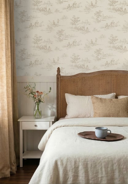 Schlafzimmer mit Toile-de-Jouy-Tapete, Bett mit Rattankopfteil, weißer Bettwäsche und Nachtschrank mit Blumen. Weiße Wandpaneele unter der Tapete.