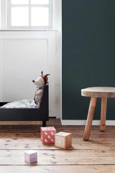 Kinderszene mit Bett, Stofftier, Spielwürfeln und Holzhocker auf Holzboden