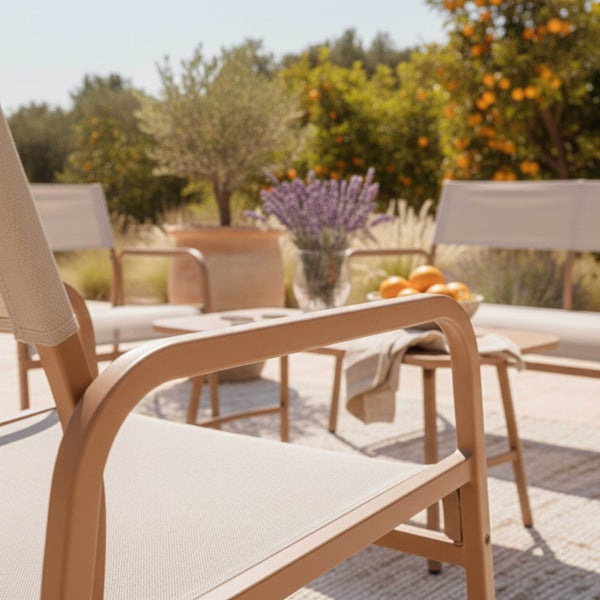 Modernes Gartenmöbel-Lounge-Set mit Metallstühlen und Textilbespannung auf einer sonnigen Terrasse mit mediterraner Dekoration.