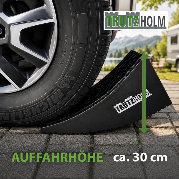 Trutzholm Auffahrkeil für Wohnwagen und Wohnmobile mit einer Auffahrhöhe von circa 30 Zentimetern unter einem Reifen. Trutzholm Logo.