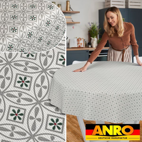 Rundes Wachstuch mit geometrischem Muster auf einem Küchentisch, Detailansichten der Struktur, ANRO Deutsche Manufaktur Logo.