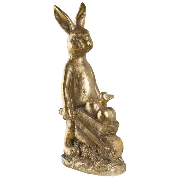 Goldfarbene Osterhasen-Figur, stehend und eine Schubkarre mit Ostereiern und einem Küken schiebend.