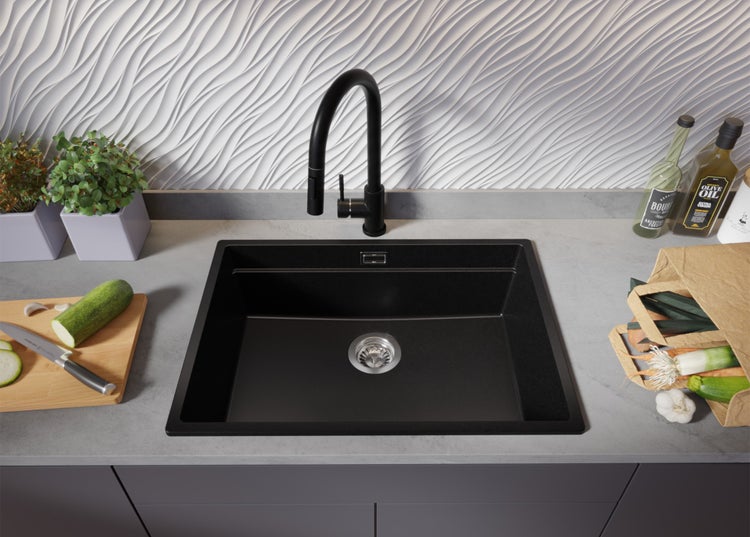 Schwarze Küchenspüle mit Armatur, Lebensmitteln und Dekoration auf einer Küchentheke.