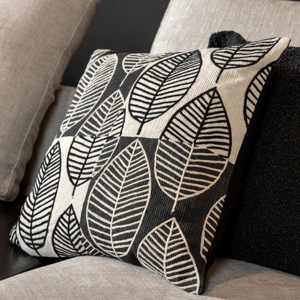 Dekokissen mit Blätterdessin auf einem Sofa.