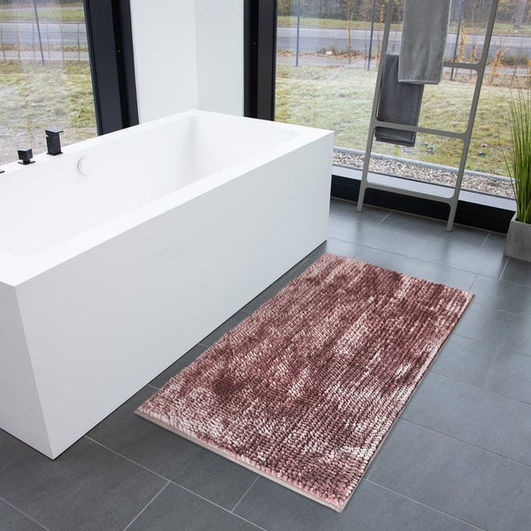 Badezimmer mit Badewanne und rosafarbener Badematte auf grauem Fliesenboden