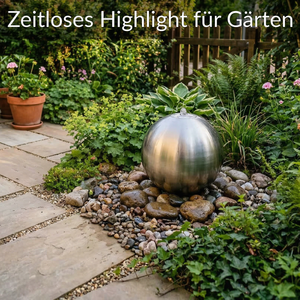 Edelstahl-Kugelbrunnen auf Flusskies in einem hellen Garten mit Steinplattenweg und Holzpforte.