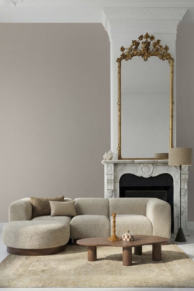 Modernes Wohnzimmer mit beige gestrichener Wand, strukturiertem Sofa, Holztisch und prunkvollem Spiegel über einem Kamin aus Marmor.