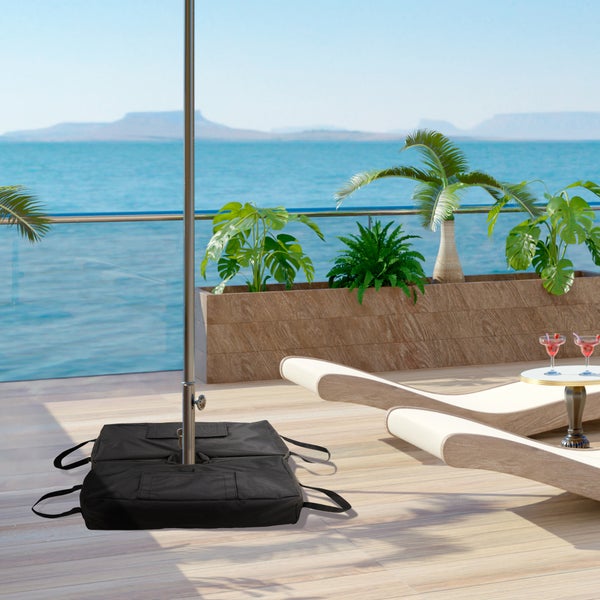 Schwarze Gewichte für einen Sonnenschirmständer auf einer sonnigen Terrasse mit Holzdeck, Pflanzen, Liegestühlen und Meerblick.