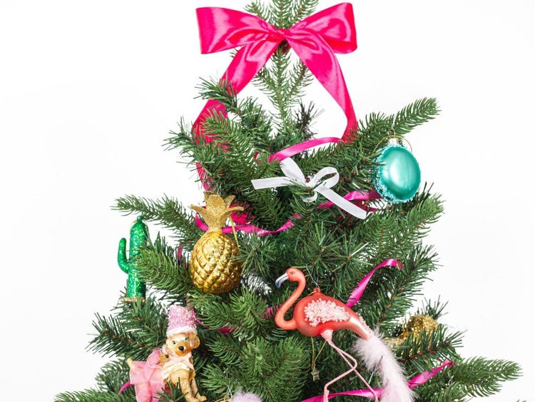 Weihnachtsbaum geschmückt mit ausgefallenen Anhängern wie Ananas, Flamingo, Kaktus und Hundefigur sowie dekorativen Schleifen