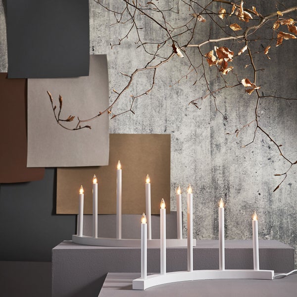 Zwei weiße Lichterbögen mit jeweils sieben Lampen auf einem Podest, dekoriert mit Ästen.