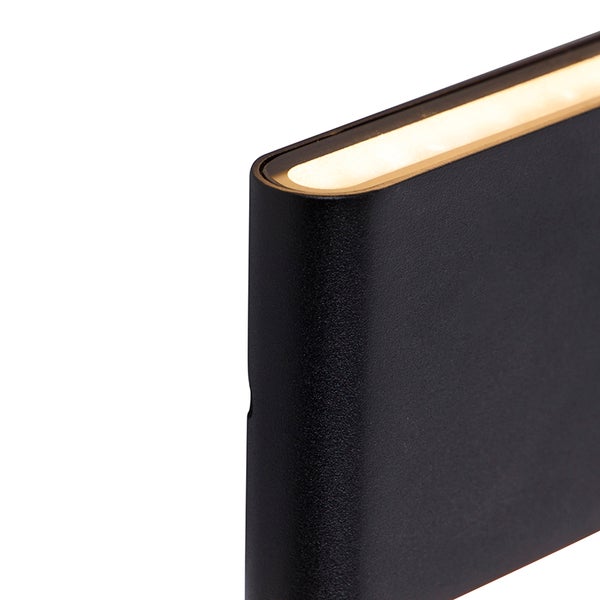 Detailansicht einer schwarzen Wandleuchte mit warmweißem Lichtaustritt.