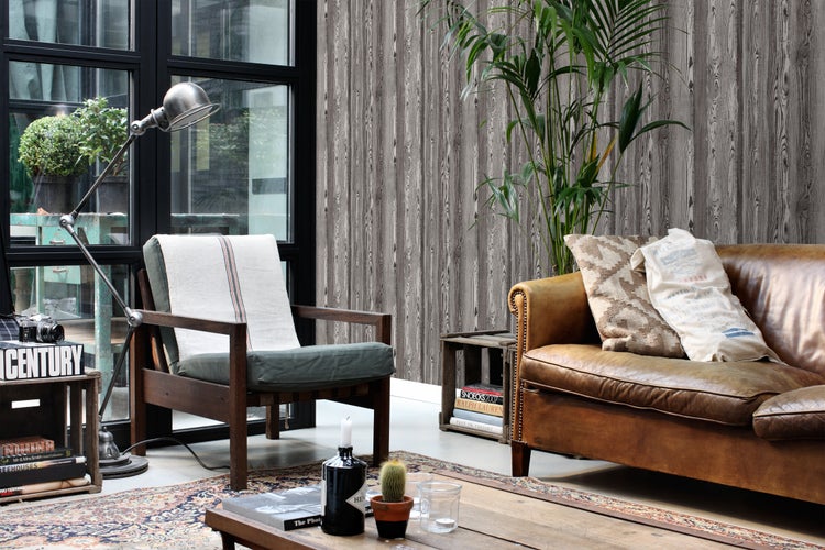 Wohnzimmer mit braunem Ledersofa, Holzstuhl und Wandtapete in Holzoptik