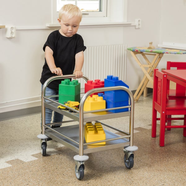 Kind schiebt einen Servierwagen mit Spielzeugklötzen