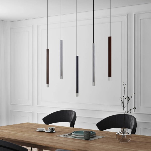 Fünf schlanke Pendelleuchten über einem Holztisch in einem modern eingerichteten Esszimmer mit weißen Wandpaneelen.