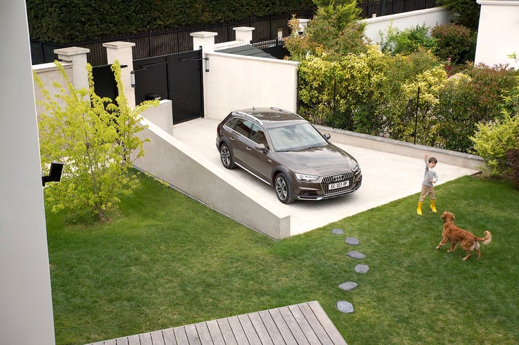 Szene im Freien mit Auto auf einer Einfahrt, Kind und Hund spielen im Garten.