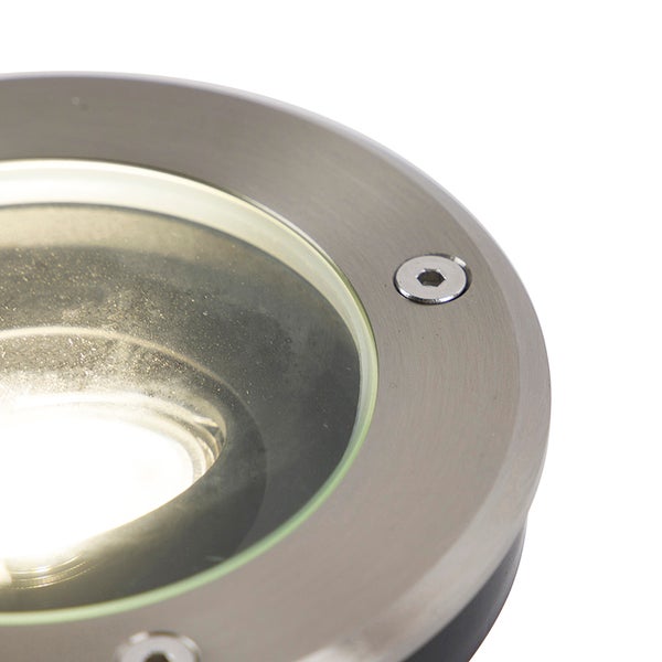 Nahaufnahme eines runden Bodeneinbaustrahlers aus gebürstetem Edelstahl mit Glasabdeckung und eingeschaltetem Licht.