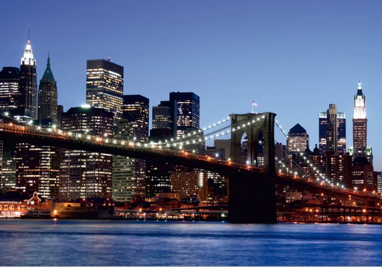 Nachtansicht der beleuchteten Brooklyn Bridge vor der Skyline von New York.
