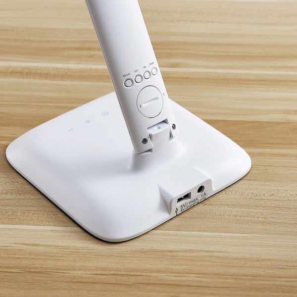 Sockel einer weißen Schreibtischlampe mit USB Ladeanschluss und Bedienelementen zur Einstellung von Helligkeit und Modus am Lampenhals.