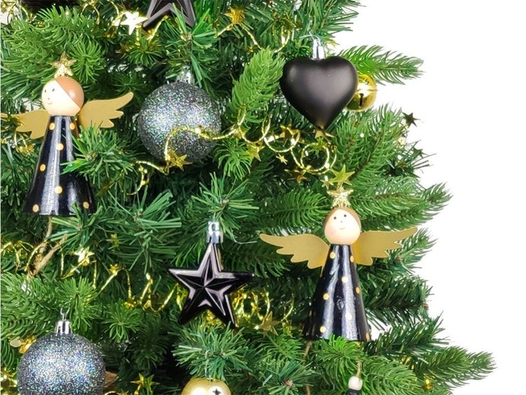 Weihnachtsbaum mit verschiedenen Anhängern wie Engeln aus Holz, Sternen und Kugeln mit Glitter sowie einer Girlande dekoriert.
