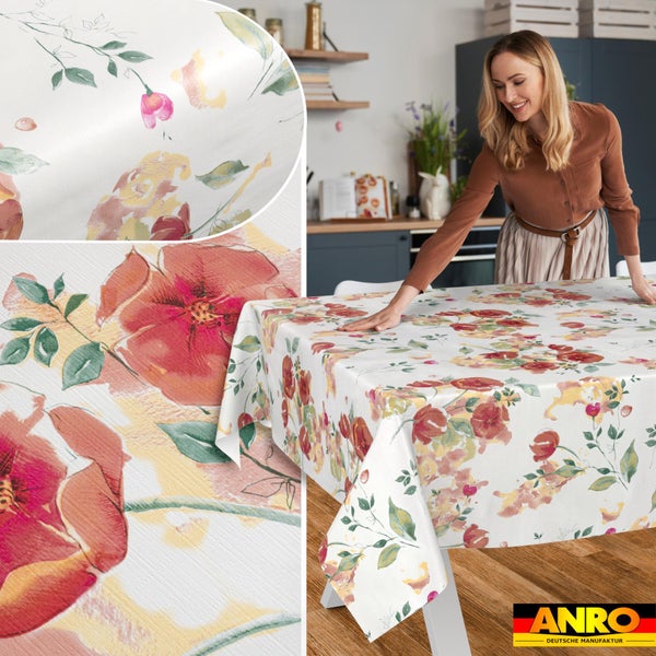 Eine Frau legt eine Tischdecke mit Blumenmuster auf einen Küchentisch, Detailaufnahme der Textur und des Musters, ANRO Logo.