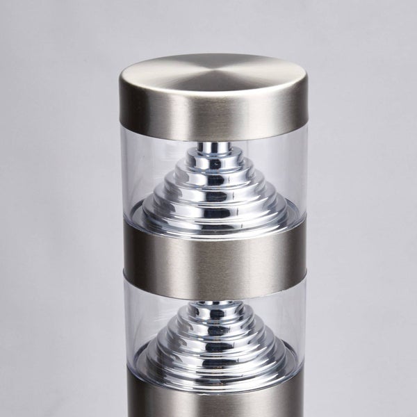 Nahaufnahme einer zylindrischen Außenleuchte aus gebürstetem Metall mit zwei transparenten Bereichen und gestuften Reflektoren im Inneren.