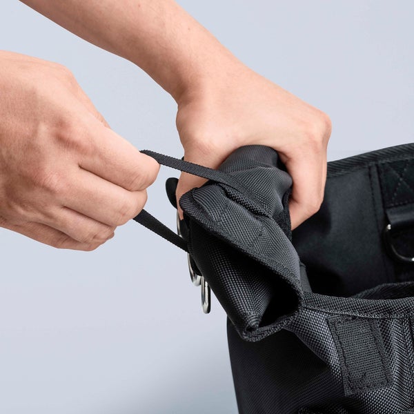 Nahaufnahme einer Person, die einen schwarzen Werkzeugrucksack mit Kordelzug hält