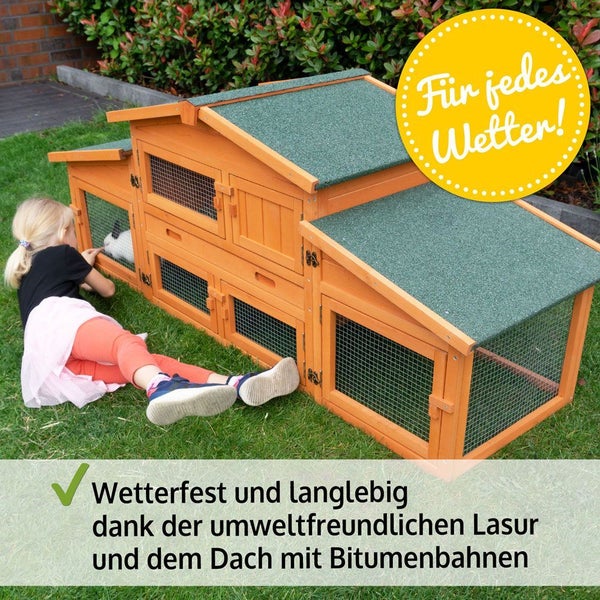 Wetterfester Kleintierstall aus Holz mit Bitumendach im Garten und ein Kind auf dem Rasen.